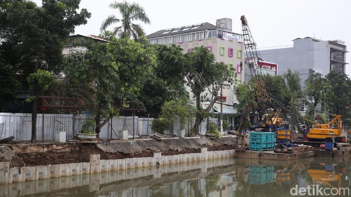 Pekerja dengan menggunakan alat berat memasang turap di pinggir Kali Ciliwung di kawasan Pasar Baru, Jakarta Pusat, Rabu (30/3/2022).