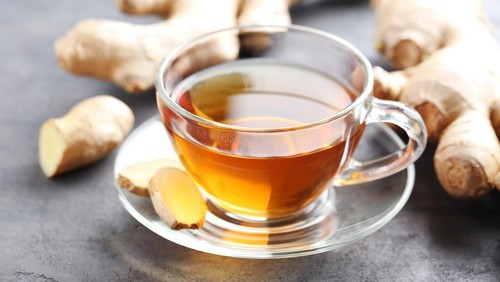 Cup of tea with ginger root on grey wooden table