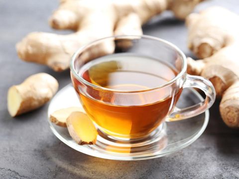 Cup of tea with ginger root on grey wooden table