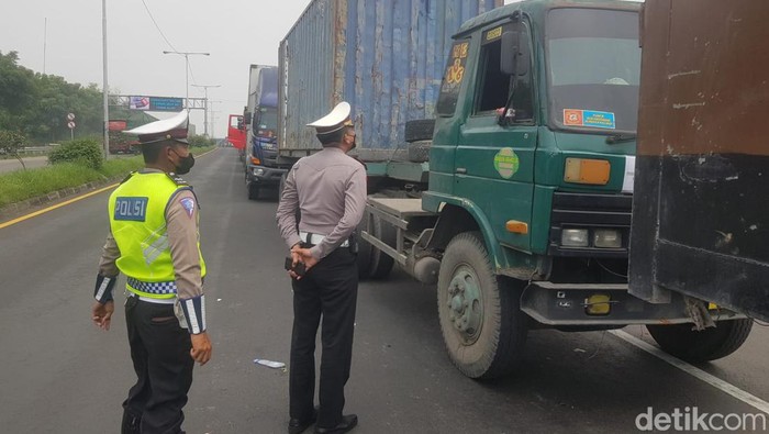 Petugas mengatur lalu lintas mengurai kemacetan panjang di exit tol Manyar Gresik dengan ekor kemacetan 3 kilometer sampai JIIPE akibat Jembatan Balun di Lamongan yang ambles.