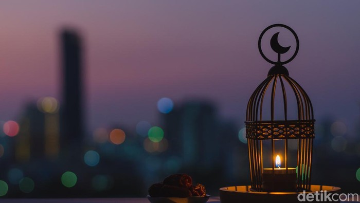 Lantern that have moon symbol on top and small plate of dates fruit with dusk sky and city bokeh light background for the Muslim feast of the holy month of Ramadan Kareem.