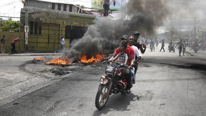 Demonstrators destroy a street sign they took down of slain President Jovenel Moise during a demonstration against increasing violence in Port-au-Prince, Haiti, Tuesday, March 29, 2022. The protest coincides with the 35th anniversary of Haiti’s 1987 Constitution and follows other protests and strikes in recent weeks in the middle of a spike in gang-related kidnappings. (AP Photo/Odelyn Joseph)