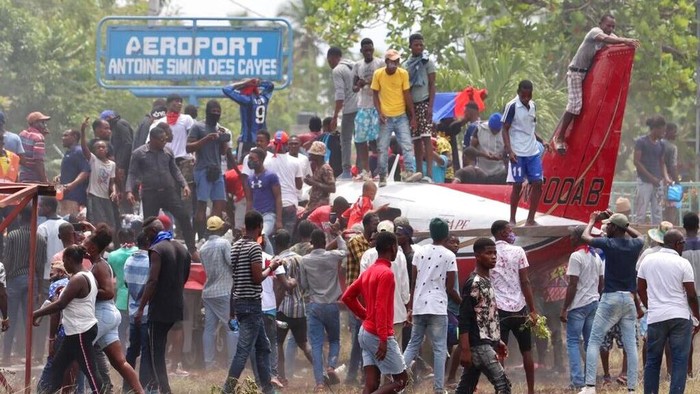 Ricuh Demo di Haiti Berakhir Bakar Pesawat People gather on and around an airplane during a protest against insecurity and violence at the Antoine Simon Des Cayes airport in Les Cayes, Haiti, Tuesday, March 29, 2022. The protest coincides with the 35th anniversary of Haitiβs 1987 Constitution and follows other protests and strikes in recent weeks in the middle of a spike in gang-related kidnappings. (AP Photo/John Cadafy Noel)