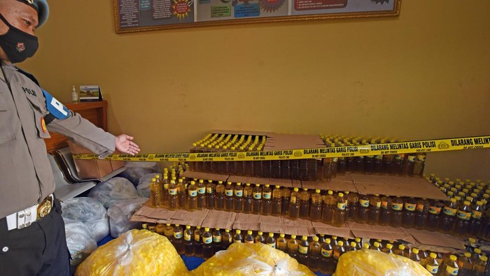 Kabid Indag Direskrimsus Polda Banten Kompol Candra Sasongko (kanan) nelihat tersangka AR (kiri) mengisi botol dengan minyak goreng curah saat rilis kasus pemalsuan minyak goreng curah menjadi minyak goreng kemasan di Serang, Banten, Rabu (30/3/2022). Jajaran Direskrimsus Polda Banten menangkap tesangka AR dan menyita 32 ribu liter minyak goreng curah serta ribuan botol kemasan minyak goreng ilegal yang sebagian telah diedarkan tersangka dengan dijual seharga Rp20 ribu per liter. ANTARA FOTO/Asep Fathulrahman/aww.