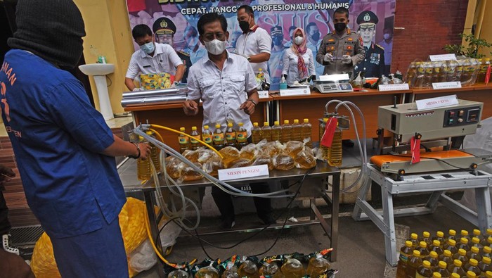 Kabid Indag Direskrimsus Polda Banten Kompol Candra Sasongko (kanan) nelihat tersangka AR (kiri) mengisi botol dengan minyak goreng curah saat rilis kasus pemalsuan minyak goreng curah menjadi minyak goreng kemasan di Serang, Banten, Rabu (30/3/2022). Jajaran Direskrimsus Polda Banten menangkap tesangka AR dan menyita 32 ribu liter minyak goreng curah serta ribuan botol kemasan minyak goreng ilegal yang sebagian telah diedarkan tersangka dengan dijual seharga Rp20 ribu per liter. ANTARA FOTO/Asep Fathulrahman/aww.