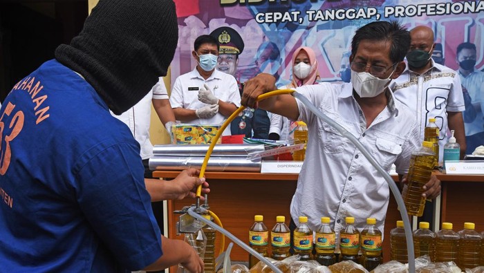 32 Ribu Liter Minyak Goreng Palsu Disita Polisi Kabid Indag Direskrimsus Polda Banten Kompol Candra Sasongko (kanan) nelihat tersangka AR (kiri) mengisi botol dengan minyak goreng curah saat rilis kasus pemalsuan minyak goreng curah menjadi minyak goreng kemasan di Serang, Banten, Rabu (30/3/2022). Jajaran Direskrimsus Polda Banten menangkap tesangka AR dan menyita 32 ribu liter minyak goreng curah serta ribuan botol kemasan minyak goreng ilegal yang sebagian telah diedarkan tersangka dengan dijual seharga Rp20 ribu per liter. ANTARA FOTO/Asep Fathulrahman/aww.