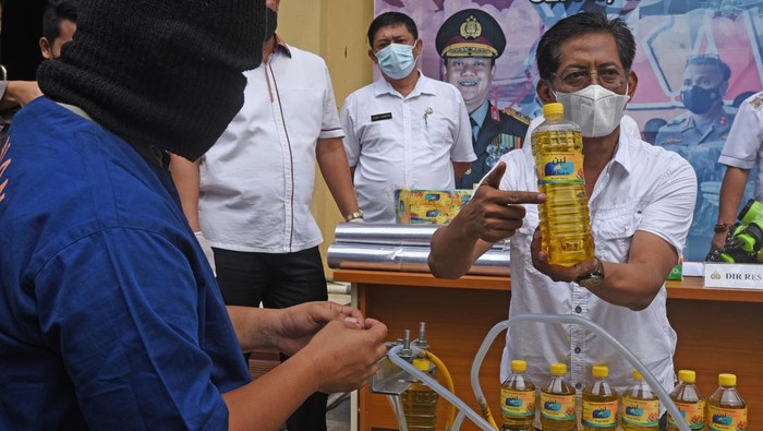 32 Ribu Liter Minyak Goreng Palsu Disita Polisi Kabid Indag Direskrimsus Polda Banten Kompol Candra Sasongko (kanan) nelihat tersangka AR (kiri) mengisi botol dengan minyak goreng curah saat rilis kasus pemalsuan minyak goreng curah menjadi minyak goreng kemasan di Serang, Banten, Rabu (30/3/2022). Jajaran Direskrimsus Polda Banten menangkap tesangka AR dan menyita 32 ribu liter minyak goreng curah serta ribuan botol kemasan minyak goreng ilegal yang sebagian telah diedarkan tersangka dengan dijual seharga Rp20 ribu per liter. ANTARA FOTO/Asep Fathulrahman/aww.