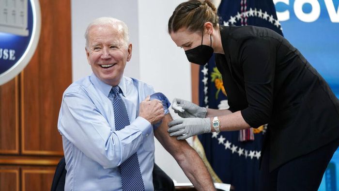 President Joe Biden prepares to roll up his sleeve before receiving his second COVID-19 booster shot in the South Court Auditorium on the White House campus, Wednesday, March 30, 2022, in Washington. (AP Photo/Patrick Semansky)