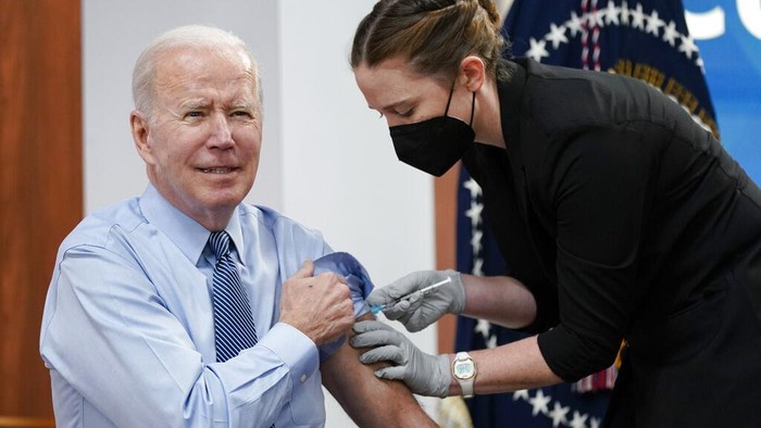 President Joe Biden prepares to roll up his sleeve before receiving his second COVID-19 booster shot in the South Court Auditorium on the White House campus, Wednesday, March 30, 2022, in Washington. (AP Photo/Patrick Semansky)
