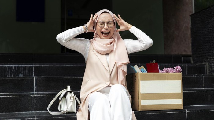 portrait of troubled and scaredmuslim lady, crying and screaming due to losing work. office worker holding head tearing hair sitting outside of her workplace