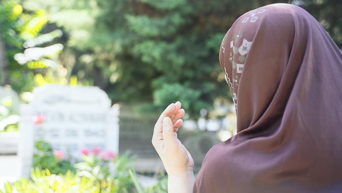 Muslim woman praying in cemetery - Rear view