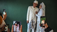 Keluarga memotret pasangan pengantin yang telah menjalani akad saat mengikuti nikah massal di Masjid Al Ukhuwah, Bandung, Jawa Barat, Kamis (31/3/2022).