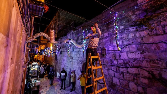 Kota Tua Yerusalem Bersolek Sambut Bulan Ramadan A man hangs decorations ahead of the holy month of Ramadan in Jerusalem's Old City, March 29, 2022. Picture taken March 29, 2022. REUTERS/Ammar Awad