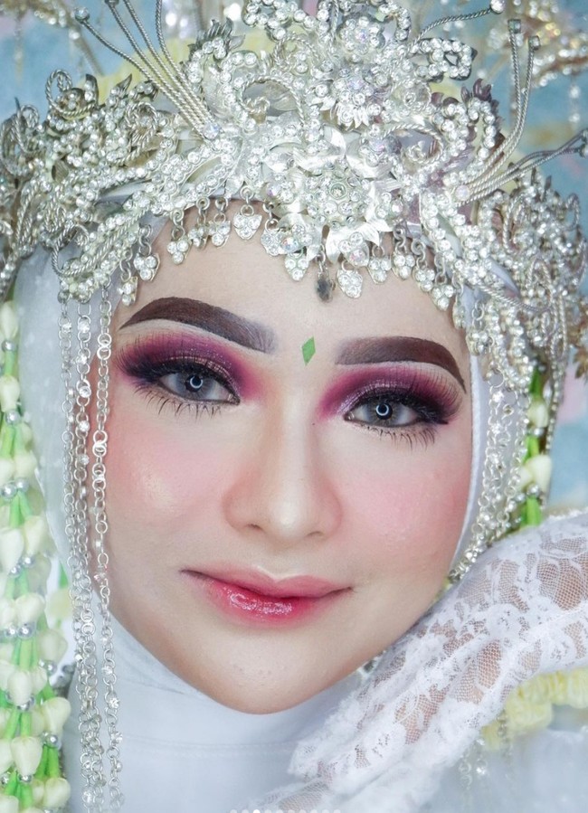 Kepada Wolipop, Putri selaku MUA sekaligus orang yang mengunggah video tersebut menjelaskan bahwa untuk mendandani modelnya itu, ia membutuhkan waktu sekitar 1,5 jam. Untuk konsepnya sendiri Putri memilih menggunakan Siger Sunda modifikasi dengan Barbie makeup look untuk wedding. Foto: Instagram/@tangancantikputri