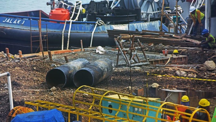 Sejumlah pekerja menyelesaikan renovasi penambahan fasilitas dan kapasistas Dermaga I Pelabuhan Merak di Cilegon, Banten, Rabu (30/3/2022). Pihak pengelola pelabuhan penyeberangan Merak merenovasi pembangunan Dermaga I dengan menambah fasilitas transit penumpang dan kapasitas kapal dari semula lebar 8 meter menjadi 12,5 meter dan kapasitas muatan yang semula 35 ton menjadi 60 ton yang ditargetkan selesai tanggal 15 April 2022 untuk memperlancar arus penyeberangan ke Pulau Sumatera. ANTARA FOTO/Asep Fathulrahman/aww.