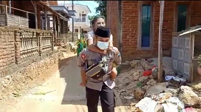 Anggota Polres Sumenep Bripka Hamsun saat menggendong Bu Atun warga Pulau Kangean untuk vaksinasi COVID-19 pertama.