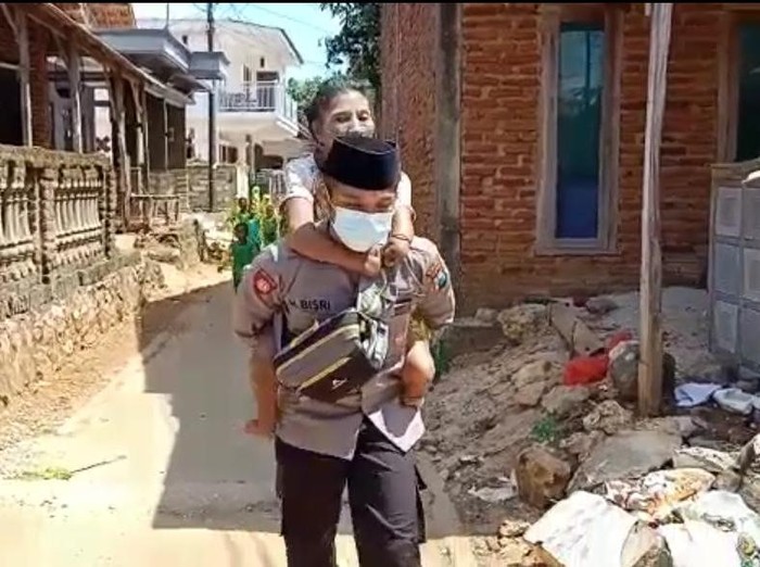 Anggota Polres Sumenep Bripka Hamsun saat menggendong Bu Atun warga Pulau Kangean untuk vaksinasi COVID-19 pertama.