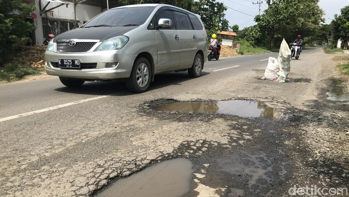 Warga memasang karung di jalan rusak yang berada di Rembang.