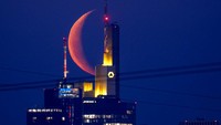 Bulan terbit dengan semburat merah di atas langit Frankfurt, Jerman, Senin (28/3/2022). Sekedar membuka jendela dan melihat ke luar adalah pekerjaan ringan yang sering teralihkan dengan keasikan di depan layar gawai. (AP Photo/Michael Probst)