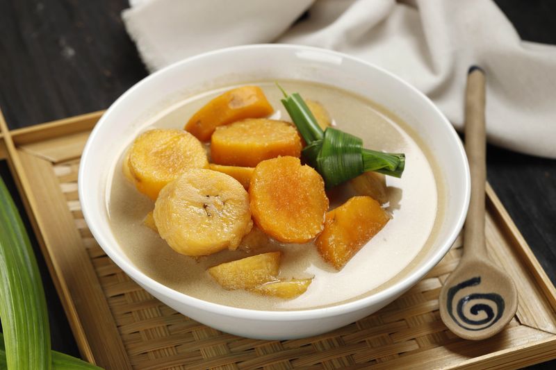 Kolak Pisang Ubi, Indonesian Popular Dessert for Takjil Ramdan Breaking the Fast, Sweet Soup Made from Banana and Sweet Potato, on Wooden Table
