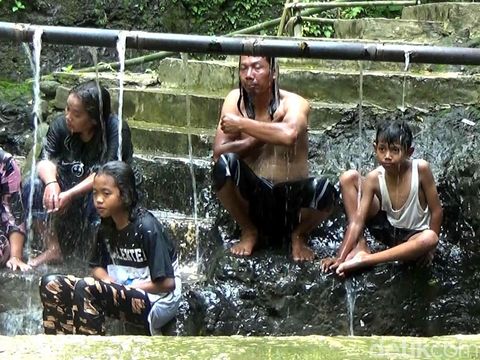 Warga mandi di bawah pancuran air hangat di Desa Gumelem Wetan, Kecamatan Susukan.