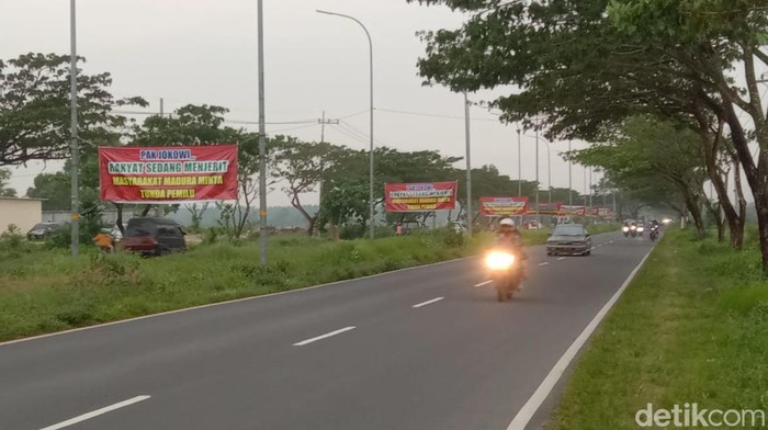 Sejumlah spanduk permintaan penundaan pemilu berjajar di sepanjang jalan akses keluar dari Suramadu.
