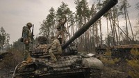 Seorang prajurit Ukraina mengambil selfie berdiri di atas tank Rusia yang hancur setelah pasukan Ukraina menyerbu posisi Rusia di luar Kyiv, Ukraina. (AP/Vadim Ghirda)