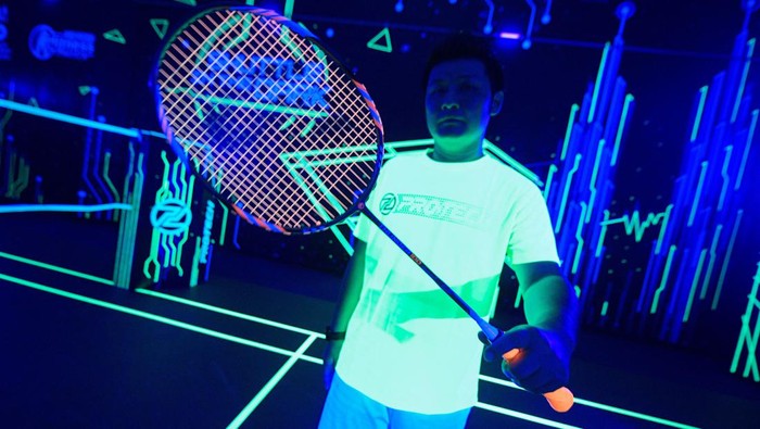 A woman plays glow-in-the-dark badminton with a shuttlecock and court lit up in neon colours in Kuala Lumpur, Malaysia, March 24, 2022. Picture taken on March 24, 2022. REUTERS/Hasnoor Hussain