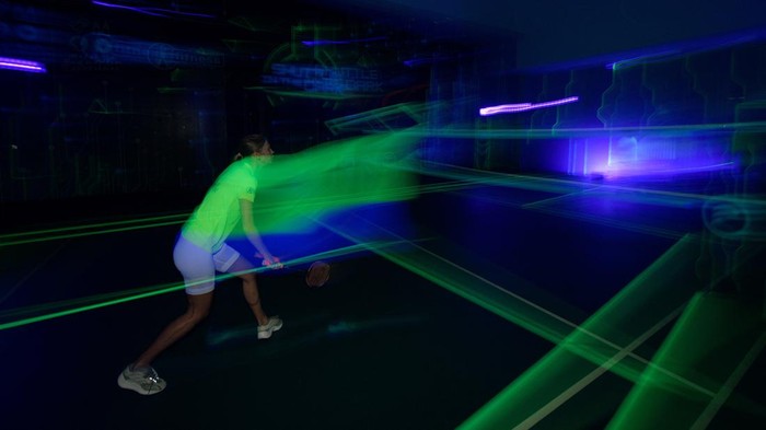 A woman plays glow-in-the-dark badminton with a shuttlecock and court lit up in neon colours in Kuala Lumpur, Malaysia, March 24, 2022. Picture taken on March 24, 2022. REUTERS/Hasnoor Hussain