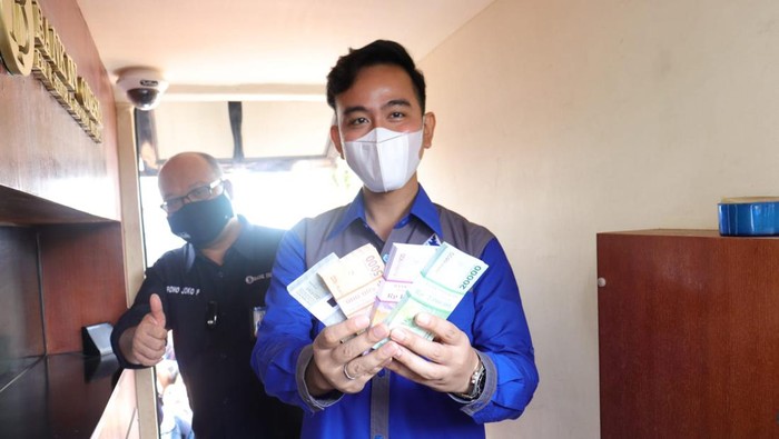Wali Kota Solo Gibran Rakabuming menunjukkan penukaran uang baru untuk Ramadan 2022