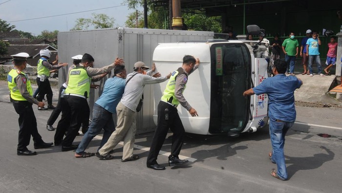 Petugas polisi dibantu warga mendorong truk yang terbalik karena kecelakaan di Jalan Solo-Jogja perbatasan Kabupaten Sukoharjo, Boyolali dan Klaten, Jawa Tengah, Sabtu (2/4/2022). Kecelakaan yang melibatkan tiga truk dan satu mobil itu masih dalam proses penyelidikan pihak polisi. ANTARA FOTO/Aloysius Jarot Nugroho/foc.