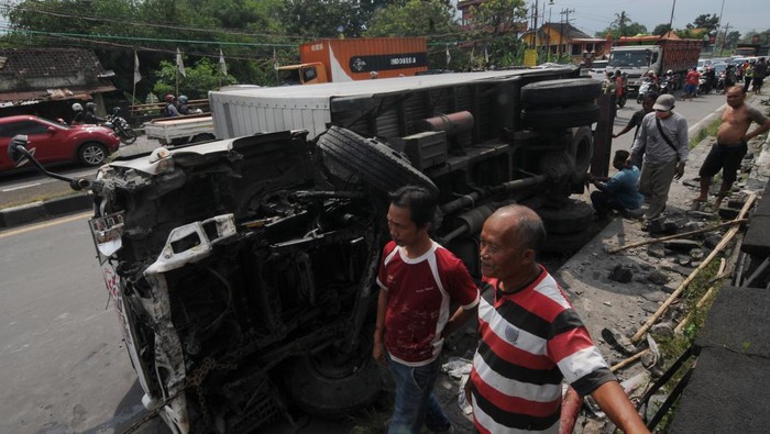 Petugas polisi dibantu warga mendorong truk yang terbalik karena kecelakaan di Jalan Solo-Jogja perbatasan Kabupaten Sukoharjo, Boyolali dan Klaten, Jawa Tengah, Sabtu (2/4/2022). Kecelakaan yang melibatkan tiga truk dan satu mobil itu masih dalam proses penyelidikan pihak polisi. ANTARA FOTO/Aloysius Jarot Nugroho/foc.