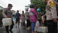 Polisi membantu seorang penyandang disabilitas yang ikut mengantre untuk membeli minyak goreng curah di salah satu agen minyak goreng di kawasan Pucang Adi, Surabaya, Jawa Timur.