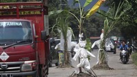 Warga daerah setempat memberi tanda pada lubang jalan dengan menanam tanaman tebu dan pisang sekaligus memasang baju alat pelindung diri (APD) bekas sebagai bentuk protes karena jalan rusak yang tidak kunjung diperbaiki.