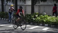 Dua orang warga menggowes sepedanya melintasi kawasan Bundaran HI.