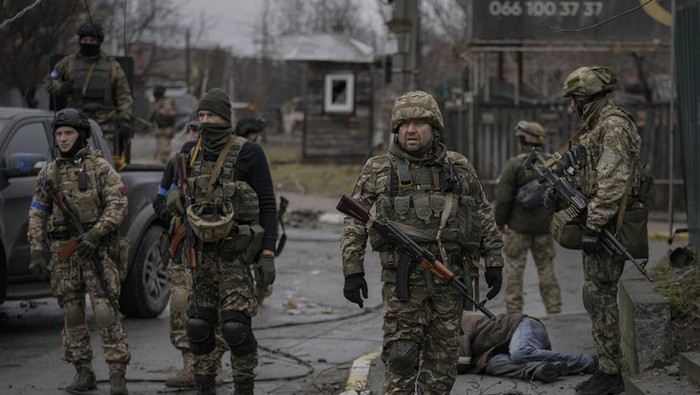 Ukrainian servicemen stand while checking bodies of civilians for booby traps, in the formerly Russian-occupied Kyiv suburb of Bucha, Ukraine, Saturday, April 2, 2022. As Russian forces pull back from Ukraines capital region, retreating troops are creating a 