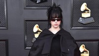 Billie Eilish memadu gaun hitam dengan outer berbentuk jas superbesar yang dipasang tak normal. (Foto: Jordan Strauss/Invision/AP/Jordan Strauss)