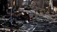 Sejumlah tentara berjalan melewati tank dan kendaraan lapis baja Rusia yang hancur di tengah invasi Rusia ke Ukraina di wilayah Bucha, yang berada di wilayah Kyiv, Sabtu (2/4/2022). REUTERS/ZOHRA BENSEMRA.