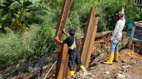  Alat berat dikerahkan untuk membantu pekerja menyelesaikan perbaikan tanggul tersebut.