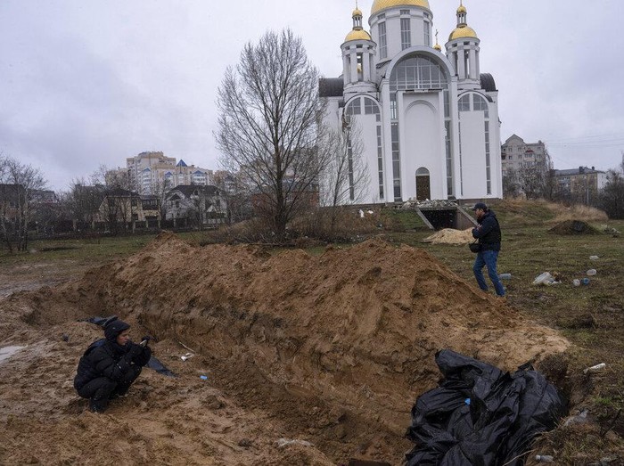 Journalists take pictures next to a mass grave in Bucha, in the outskirts of Kyiv, Ukraine, Sunday, April 3, 2022. (AP Photo/Rodrigo Abd)