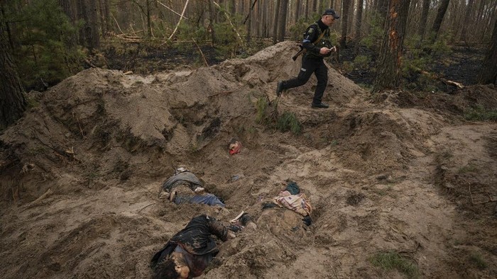 Journalists take pictures next to a mass grave in Bucha, in the outskirts of Kyiv, Ukraine, Sunday, April 3, 2022. (AP Photo/Rodrigo Abd)