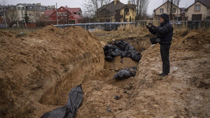 Journalists take pictures next to a mass grave in Bucha, in the outskirts of Kyiv, Ukraine, Sunday, April 3, 2022. (AP Photo/Rodrigo Abd)