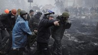 Pengunjuk rasa anti-pemerintah membawa seorang pria yang terluka di atas tandu setelah bentrokan dengan polisi anti huru hara di Lapangan Kemerdekaan di Kyiv, Ukraina, (20/2/2014). REUTERS/Maksim Levin