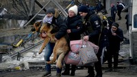 Seorang pria membawa seekor anjing saat orang-orang melarikan diri, di tengah invasi Rusia ke Ukraina, di Irpin, Ukraina, (9/3/2022). Levin telah bekerja di desa Huta Mezhyhirska. Terjadi pengeboman besar-besaran di daerah itu. Kantor kejaksaan di Ukraina mengatakan Levin dibunuh oleh prajurit Angkatan Bersenjata Rusia dengan dua tembakan dari senjata ringan. Namun tidak dapat diverifikasi secara independen. REUTERS/Maksim Levin