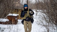 Fotografer Ukraina Maksim Levin membawa seekor kucing di dekat garis pemisahan dari separatis yang didukung Rusia di wilayah Donetsk, Ukraina, (25/1/2022). Levin, lahir pada 1981, adalah seorang pembuat film dokumenter yang telah berkontribusi pada liputan Reuters di negara itu sejak 2013. REUTERS/Stringer