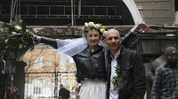 Anastasia dan Anton berpose untuk foto pernikahan mereka di halaman gedung apartemen yang hancur imbas perang Rusia-Ukraina di kawasan Kharkiv, Minggu (3/4/2022).