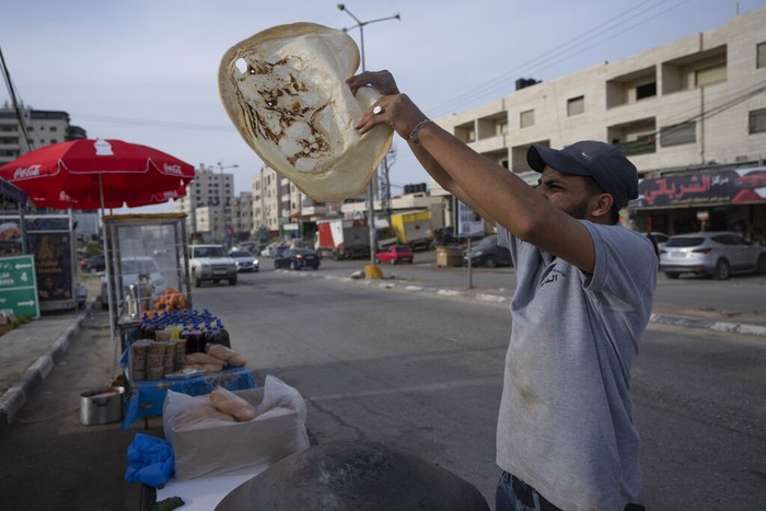 A Palestinian street vendor bakes Shrak bread, widely desired while breaking fast in Ramadan, in the West Bank city of Ramallah, Saturday, April 2, 2022. The Muslim holy month of Ramadan, when the faithful fast from dawn to dusk, began at sunrise Saturday in much of the Middle East, where Russia's invasion of Ukraine has sent energy and food prices soaring. (AP Photo/Nasser Nasser)