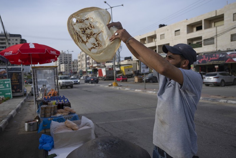 A Palestinian street vendor bakes Shrak bread, widely desired while breaking fast in Ramadan, in the West Bank city of Ramallah, Saturday, April 2, 2022. The Muslim holy month of Ramadan, when the faithful fast from dawn to dusk, began at sunrise Saturday in much of the Middle East, where Russia's invasion of Ukraine has sent energy and food prices soaring. (AP Photo/Nasser Nasser)