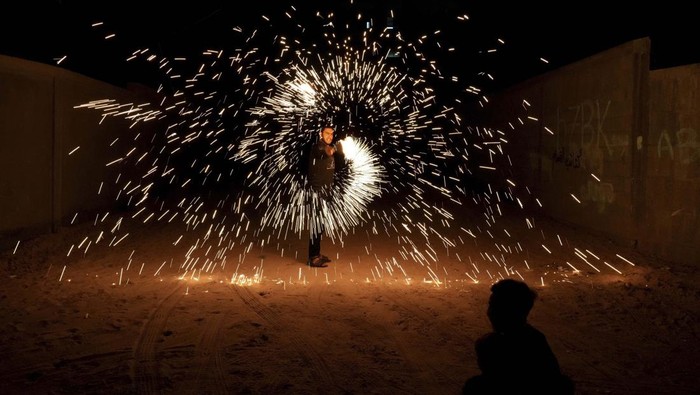 A man swings fireworks during the Muslim holy fasting month of Ramadan, in Gaza City, Saturday, April 2, 2022. (AP Photo/Hatem Moussa)