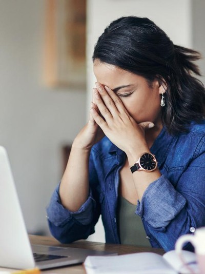 875247462 Shot of a young woman looking stressed while using a laptop to work from home